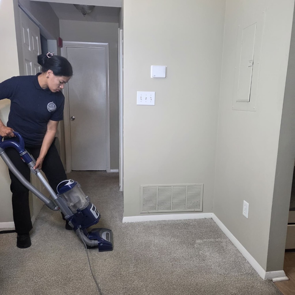 An L&G owner vacuuming a hallway carpet